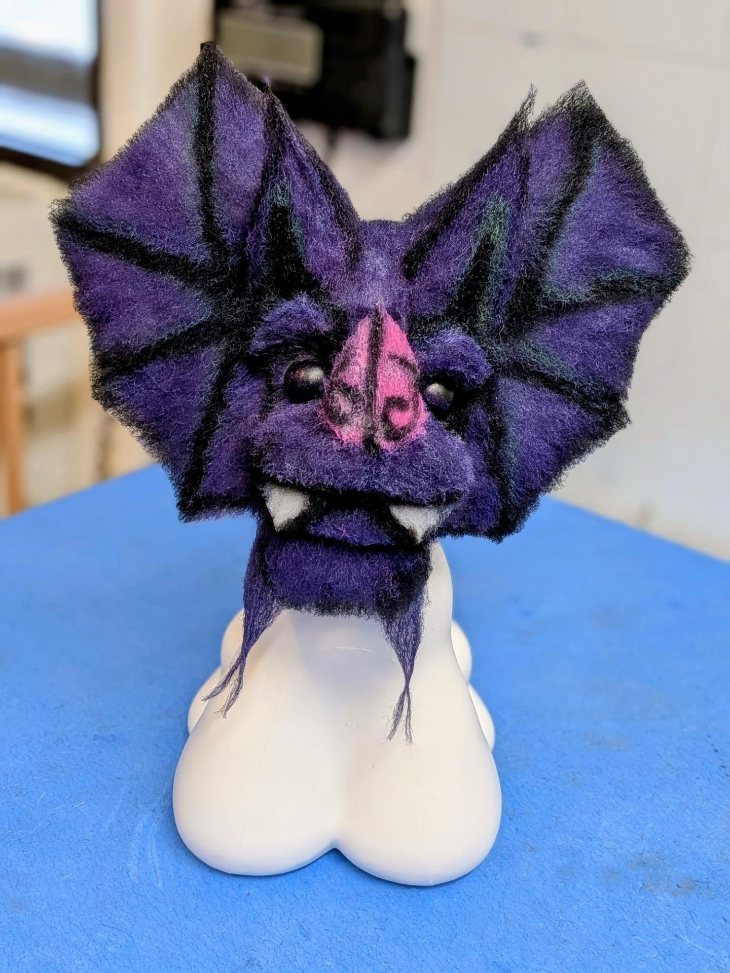 Purple and black bat creative groom on a model dog head, with carved wing structure and pink muzzle detail.
